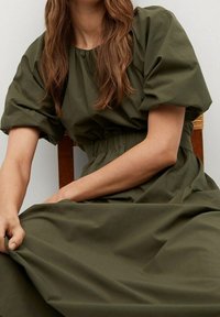 Olivengrünes Baumwollkleid mit puffärmeligen kurzen Ärmeln, gerafftem Taillenbereich und fließendem Rock. Glatte Textur, lässiges Design.