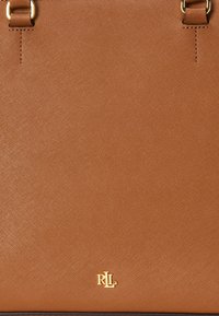 Barna texturált bőr bevásárlótáska aranyszínű RLL logóval és aranyszínű fémalkatrészekkel, amelyek a fogantyúkhoz vannak rögzítve.