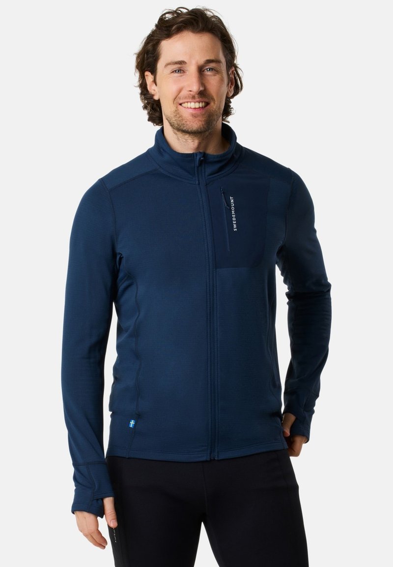 Dunkelblaue Fleece-Jacke mit Reißverschluss und Stehkragen, schlanker Schnitt, sichtbare Nähte, Seitentaschen und kleinem Logo auf der Brust. Weicher Stoff.