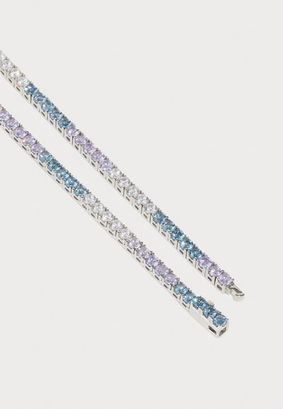 Pulsera de tono plateado que presenta filas alternas de cristales en azul claro, púrpura y transparente, con un diseño lineal y elegante.