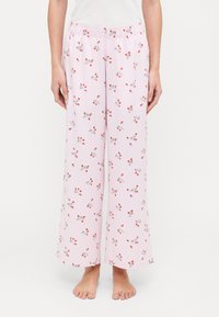 Pantaloni da pigiama leggeri rosa con un motivo a quadri e piccoli fiori rossi e foglie verdi. Vita elastica, gambe larghe.