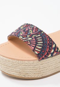 Sandale à talon compensé ouverte à l'avant, avec plateforme en jute tissé et large bride en tissu présentant un motif cachemire complexe rouge, marine et crème.