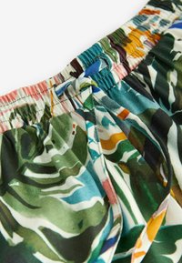 Shorts à motif floral en tissu léger. La taille élastique est dotée d'un cordon de serrage. Les couleurs prédominantes incluent du vert, du bleu et des accents roses.