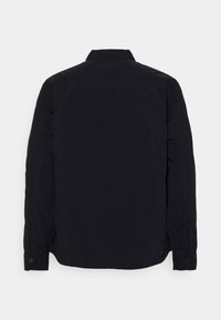 Černá košile s dlouhým rukávem z texturované látky, s hrotatým límcem, knoflíkovými manžetami a rovnýlem lemem bez viditeln ých vzorů.