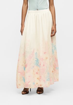 Lang cremefarvet nederdel med pastelrosa og blå blomstermønster, båret med brune åbne hæle og en lyseblå knapbluse.