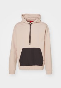 Sudadera beige con un bolsillo delantero negro, capucha con cordón y puños de canalé. Fabricada con tela suave, presenta bloques de color en contraste.