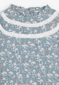 Top de tela floral azul con acentos de encaje blanco y detalle de fruncido. Pequeños patrones de flores en tonos blancos y naranjas a lo largo.