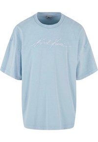 T-shirt oversize bleu clair en coton avec un col rond, présentant un logo brodé blanc sur la poitrine et des manches courtes.