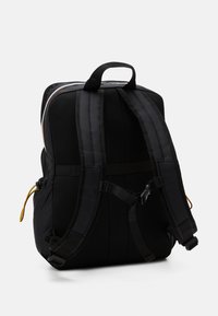 Sac à dos noir avec des bretelles en maille rembourrées, une poche avant et une poignée supérieure. Boucles réglables et détail de cordon coloré sur le côté.