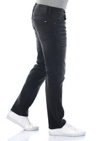 Jeans neri a taglio slim, con un classico design a cinque tasche, cuciture sottili sulle tasche e una cintura con marchio. Sneakers bianche.