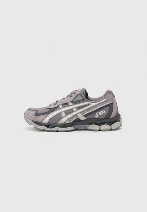Chaussure de running Asics grise et noire avec des bandes blanches du logo, en mesh et suède, et semelle amortie, vue de profil.