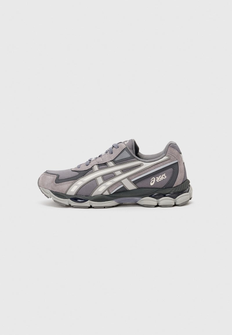 Chaussure de running Asics grise et noire avec des bandes blanches du logo, en mesh et suède, et semelle amortie, vue de profil.