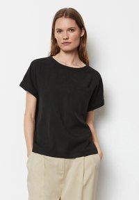 Sort bomulds T-shirt med korte ærmer, rund halsudskæring og brystlomme. Enkel, lige skåret design med blød tekstur.