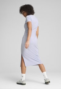 Robe ajustée lavande clair avec des manches courtes, fente au genou sur le côté, texture lisse, associée à des baskets grises et des chaussettes blanches.