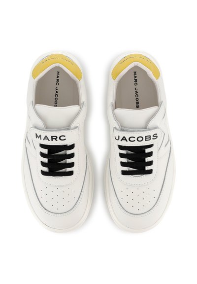 Sneaker bianche in pelle con lacci neri, punta forata e dettagli gialli sul tallone. Testo "MARC JACOBS" sulla linguetta.