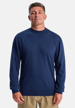 Pull en maille bleu marine à manches longues avec un col rond, texture douce, poignets et ourlet côtelés, et silhouette ajustée. Aucun motif ni ornement visible.