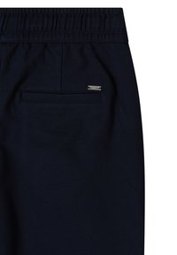 Pantalon bleu marine foncé avec taille élastique et une seule poche passepoilée à l'arrière, ornée d'une petite étiquette métallique de la marque sur le côté droit.
