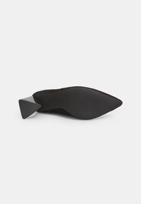 Chaussure noire en daim à bout pointu avec un talon triangulaire texturé noir et une semelle lisse, présentant un design minimaliste et des lignes épurées.