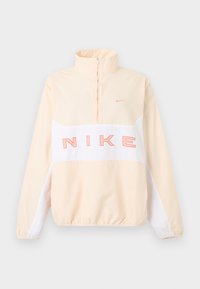 Μπεζ και λευκό πουλόβερ Nike με φερμουάρ τετάρτου μήκους, ελαστικά μανσέτες και τελείωμα, μεγάλο ροζ κείμενο "NIKE" στο στήθος και μικρό λογότυπο Swoosh στο αριστερό μέρος του στήθους.