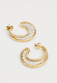 Gold hoop earrings featuring a wavy design, adorned with white pearls and clear rhinestones along the upper edge.