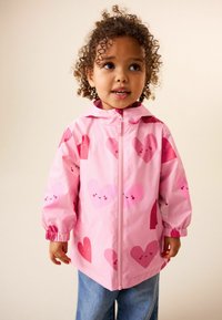 Růžová nepromokavá bunda s nadměrnými vzory srdcí v různých odstínech růžové, s elastickými manžetami a předním zipem.