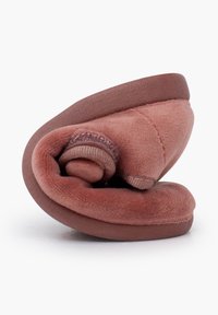Zapatilla suave rosa con tela de felpa, diseño enrollado y suela marrón resistente. Forma compacta, que enfatiza la comodidad y facilidad de almacenamiento.