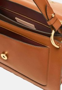 Borsa a tracolla in pelle marrone con chiusura a scatto dorata, tasca con zip e superficie liscia con un colore interno a contrasto.