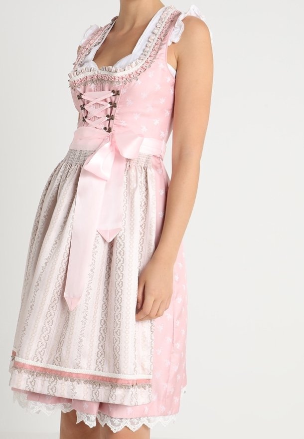 Traditional dirndl dress in light pink and white. Features lace trim, a fitted bodice with ribbon lacing, and a full skirt with floral patterns.