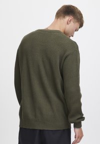 pulover texturat de culoare verde măslin, cu guler rotund și mâneci lungi, având un design tricotat texturat și o croială lejeră, prezentat din spate.