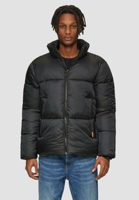 Zwarte pufferjack met een hoge kraag, ritssluiting en zijzakken. Gemaakt van soepel materiaal met een gestikt ontwerp en een oranje accent.