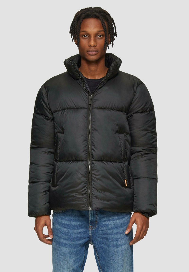 Zwarte pufferjack met een hoge kraag, ritssluiting en zijzakken. Gemaakt van soepel materiaal met een gestikt ontwerp en een oranje accent.