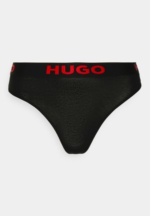 Must mustre päikesevarjuga mustad string aluspesu, millel on sile tekstuur ja kontrasteeriv punane elastne vöö, millel on prominentne brändi nimi "HUGO".