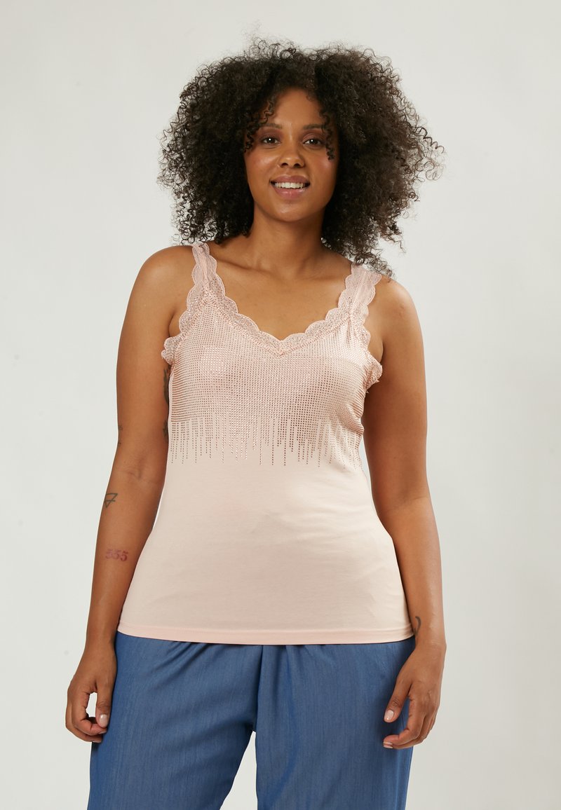 Top sin mangas rosa claro con encaje en el borde y detalles de lentejuelas en el escote, combinado con pantalones azul relajados. Textura suave, diseño casual.