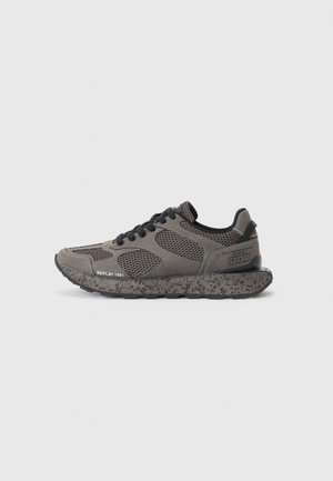 Deportiva de malla gris y negra con suela texturizada, cordones negros y texto "REPLAY 1981" en el lateral, mostrada de perfil.