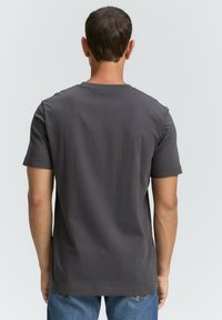 Camiseta gris de manga corta hecha de un tejido suave con un cuello redondo, que presenta una textura lisa y un ajuste relajado.
