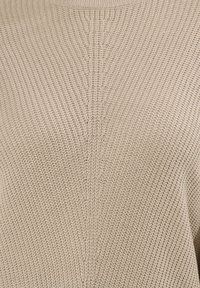 Beżowy sweter z dzianiny o strukturalnym wzorze i centralnym szwie, z okrągłym dekoltem i długimi rękawami.