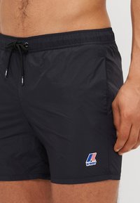 Sorte badshorts i lette materialer med snor i livet. Har en liten, flerfarget K-Way-logo på venstre side.