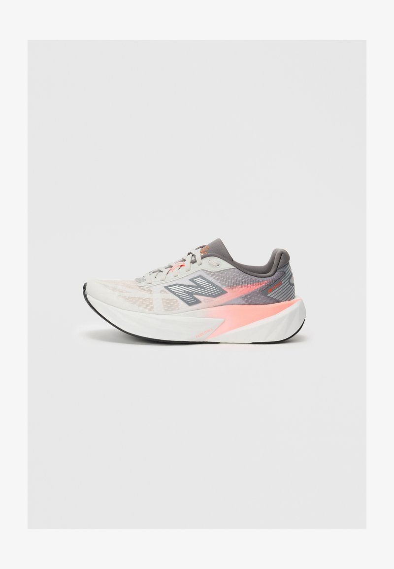 Baskets de course New Balance grises claires et roses avec une épaisse semelle blanche et une semelle extérieure noire, vue de côté sur fond uni.