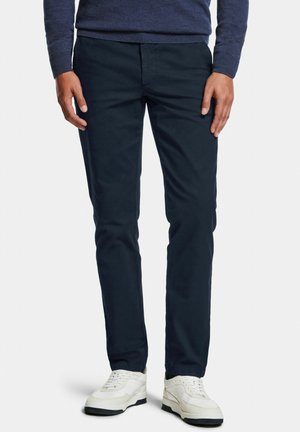Navyblaue Chinos aus Baumwolle, mit geradem Schnitt und klassischem Fünf-Taschen-Design. Getragen mit weißen Sneakern.