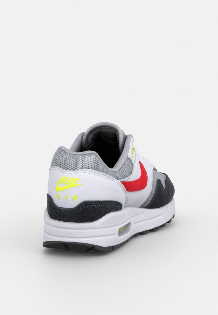 Baskets blanches, grises et noires avec des accents rouges et jaunes fluo ; elles possèdent un dessus texturé, un col rembourré et un logo de marque au niveau du talon.