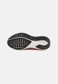 Semelle d'une chaussure de course avec une bande de roulement en caoutchouc noir et une semelle intermédiaire blanche, montrant un motif de grip texturé et un soutien de la voûte plantaire incurvée.