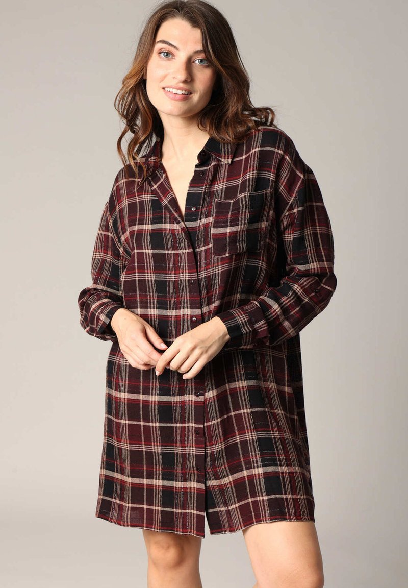 Robe chemise à carreaux rouge et noir, manches longues, fermeture à boutons sur le devant, poche poitrine unique, tissu doux avec une finition légèrement structurée.