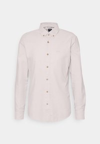 Camicia lunga beige chiaro con colletto button-down, cinque bottoni a contrasto e ricamo del logo discreto sul petto.