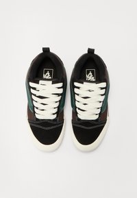 Černé a hnědé tenisky s tyrkysovými akcenty, bílé tkaničky a strukturovaným povrchem. Na jazyku se nachází logo a kontrastní prošívání.