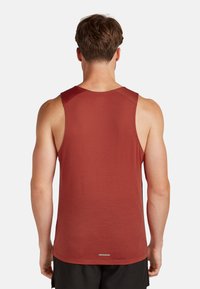 Rotes Sporttanktop aus strukturiertem Stoff, mit ärmellosem Design, gerundetem Halsausschnitt und einem reflektierenden Akzent am Saum.