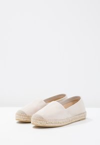 Espadrillas in tela beige con punta arrotondata, suola in corda di juta e pannelli laterali elastici. Texture liscia e design semplice senza decorazioni.
