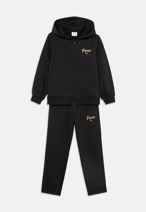 Čierna tréningová súprava Puma s mikinou na zips a zladenými nohavicami, s zlatým logom Puma na hrudi a stehne.
