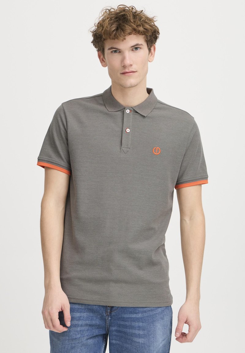 Grå polo skjorte med struktureret stof, to knapper ved kraven og orangerøde detaljer på ærmerne. Broderet logo på brystet.