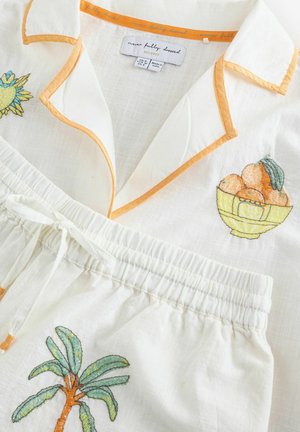 Fehér lenpizsamaszett narancssárga szegéllyel, melyen pálmafát és gyümölcstálat hímzett motívumként. Könnyű, légáteresztő anyag, rugalmas derékpánttal.