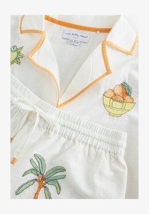 Fehér lenpizsamaszett narancssárga szegéllyel, melyen pálmafát és gyümölcstálat hímzett motívumként. Könnyű, légáteresztő anyag, rugalmas derékpánttal.